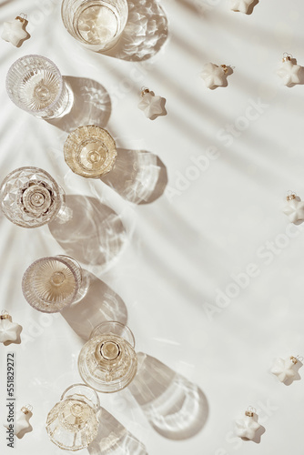 New Year holiday flat lay, white sparkling wine in different crystal glasses, festive champagne drink, beige golden aesthetic layout, new year holiday event or party concept, shadow