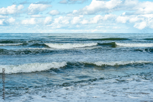 The surface of the sea with a slight wave. Blue sky with clouds over the sea.