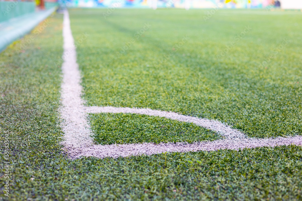 Close up shot of white line of chalk for corner symbol on lawn or grass in soccer field under sunlight in summer shows concept of sport and leisure time activities outdoor for competition.