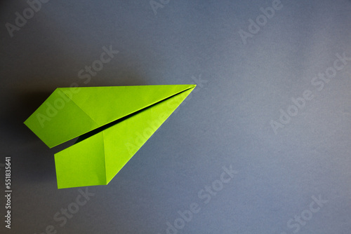 Green paper plane origami isolated on a grey background