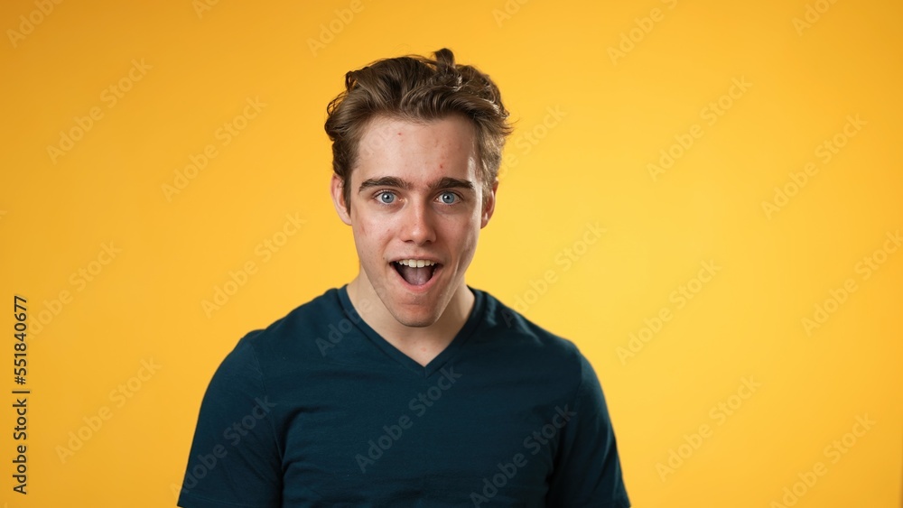 Portrait of happy young man 20s happy smiling waving hello with hand, isolated on solid yellow background. Portrait of happy young man 20s happy smiling waving hello with hand, isolated on solid yellow background.