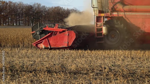 Close-up of Harvesting machine working in the field. Combine harvester agricultural machine ride in the field of goldens soybean.