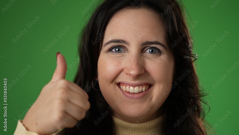 © Robert Peak - Portrait of young woman 20s giving thumbs up gesture isolated on green screen background studio closeup