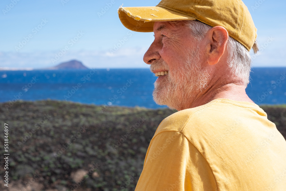 Portrait of happy bearded senior man walking on trail outdoors on seaside excursion. Relaxed caucasian man enjoying travel or retirement leading healthy lifestyle. Beautiful landscape on a sunny day Portrait of happy bearded senior man walking on trail outdoors on seaside excursion. Relaxed caucasian man enjoying travel or retirement leading healthy lifestyle. Beautiful landscape on a sunny day