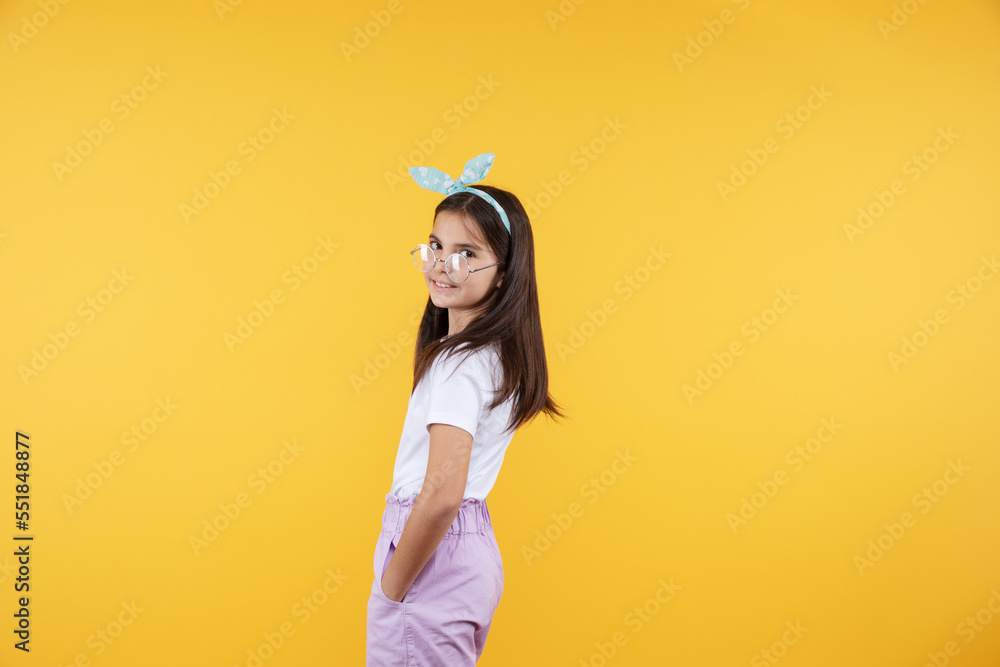 Studio portrait of cheerful 9, 10, 11 years old kid girl. Teenager child wearing glasses posing on yellow background. Cute girl in eyeglasses. Studio portrait of cheerful 9, 10, 11 years old kid girl. Teenager child wearing glasses posing on yellow background. Cute girl in eyeglasses.