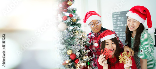 Happy Asian people enjoy decorating a Christmas tree with a fantasy Christmas balls and presents together. 