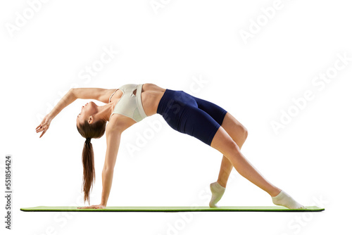 Portrait of young sportive woman training, doing full-body stretching exercises on mat isolated over white background. Concept of sport, fitness, health