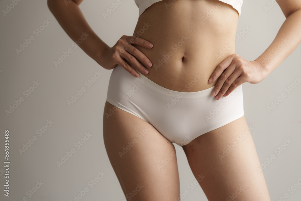 Close up asian female body wearing white high-waist panties over grey background. Close up asian female body wearing white high-waist panties over grey background.