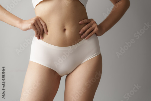 Pretty asian woman wears white lingerie poses against grey background with body care, bra, underwear concept.