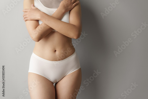 Pretty asian woman wears white lingerie poses against grey background with body care, bra, underwear concept.