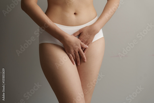 Close up asian woman cropped shot with white panties on grey background, vagina healthy concept. photo