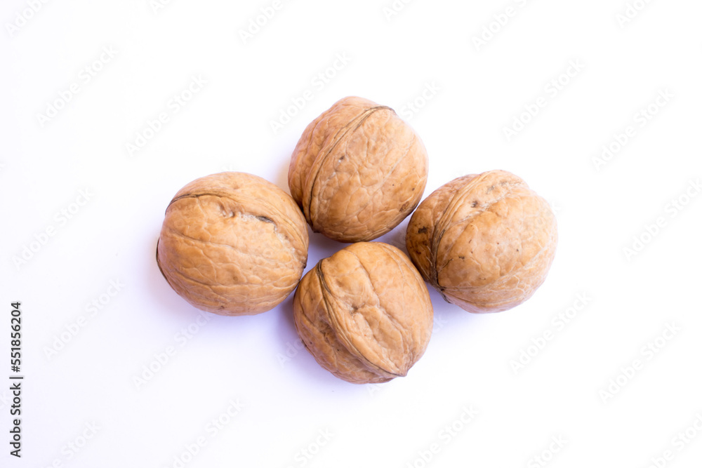 four large brown walnuts on a white background. four large brown walnuts on a white background.