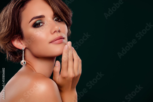Adorable girl near empty space promoting bright jewelry new year gifts for ladies isolated on green color background