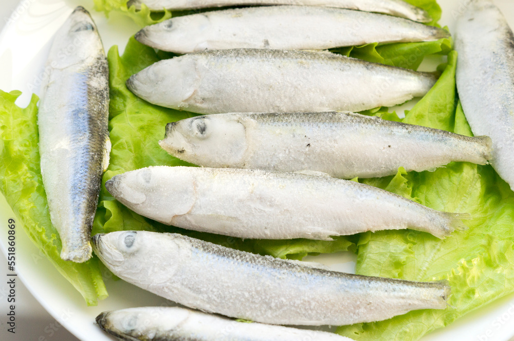 Frozen capelin fish laid out on lettuce leaves Frozen capelin fish laid out on lettuce leaves