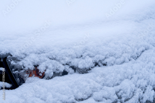 Vehicle operation in winter. View of a car headlight under a layer of snow