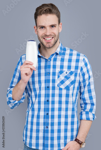 unbranded cosmetic for cheerful man. stylish man hold bottle of unbranded cosmetic.