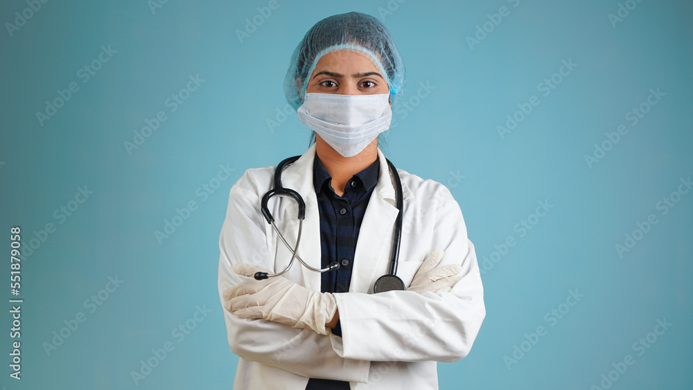Portrait of a young female doctor wearing apron and stethoscope, Cheerful Asian Indian woman doctor wearing face mask isolated over blue studio background Portrait of a young female doctor wearing apron and stethoscope, Cheerful Asian Indian woman doctor wearing face mask isolated over blue studio background