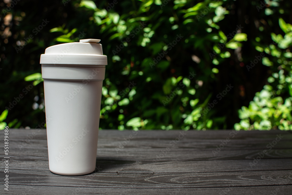white coffee cup on black wooden table with green leaves background white coffee cup on black wooden table with green leaves background