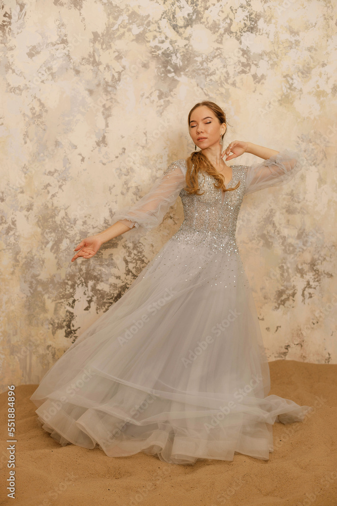 a girl in a dress on the sand against a shabby wall a girl in a dress on the sand against a shabby wall