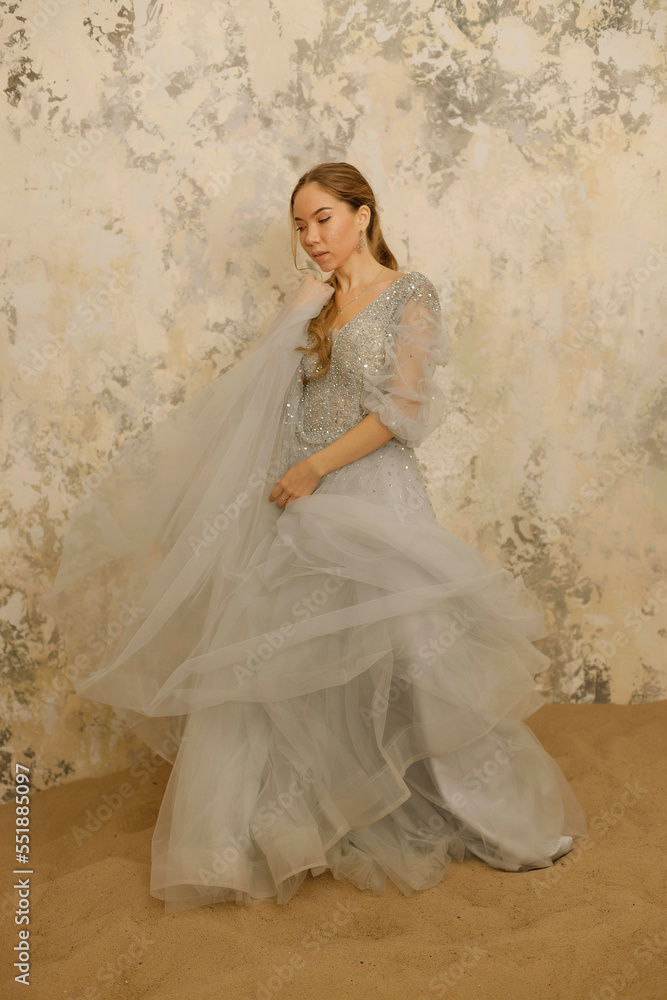 a girl in a dress on the sand against a shabby wall a girl in a dress on the sand against a shabby wall