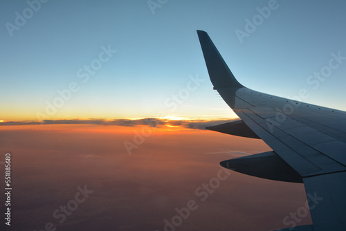 View from an airplane window showing the wing and the sunset