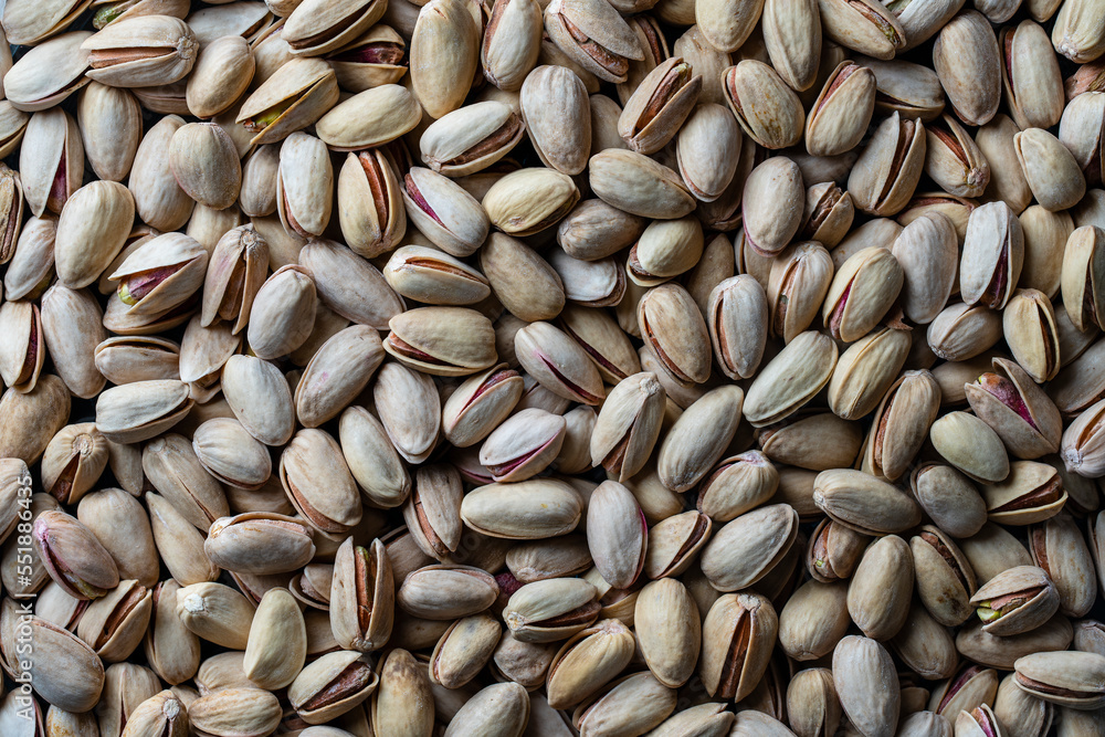 Fototapeta premium Pistachios texture and background. Pile pistachio kernels nuts with shell, closeup. Pistachio nuts. Whole nut kernels