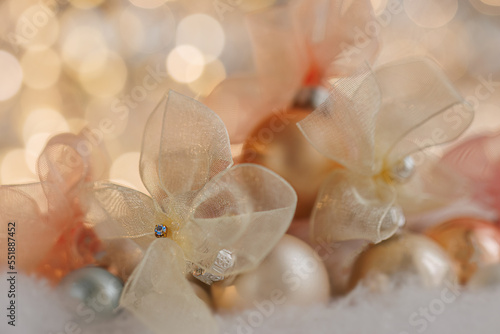Fototapeta Naklejka Na Ścianę i Meble -  Christmas or New Year festive blurred background with beige bows and balls on white snow. Shallow depth of field. Beautiful bokeh. Airy atmosphere. 