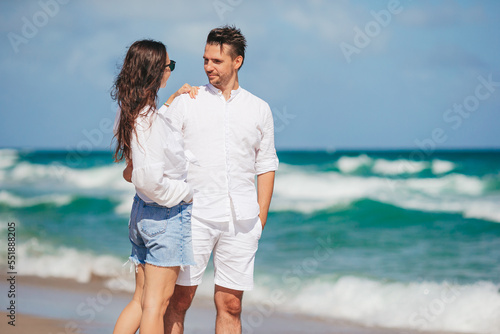 Young couple walking on the beach summer vacation. Happy man and woman look at the sea 