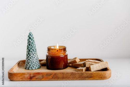 Merry Christmas decoration concept with burning candles and festive decor, christmas trees on light white background. Cozy home. Space for text.