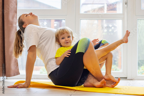 Mother and son family doing fitness, yoga, exercise on a yoga mat at home