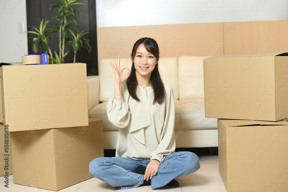 段ボール箱の前でOKサインをする若い女性
段ボール箱の前でOKサインをする若い女性