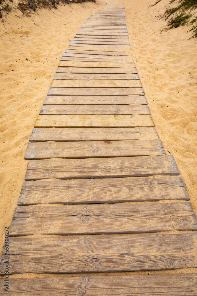 Fototapeta premium Sendero con tablones de madera sobre la arena de una playa