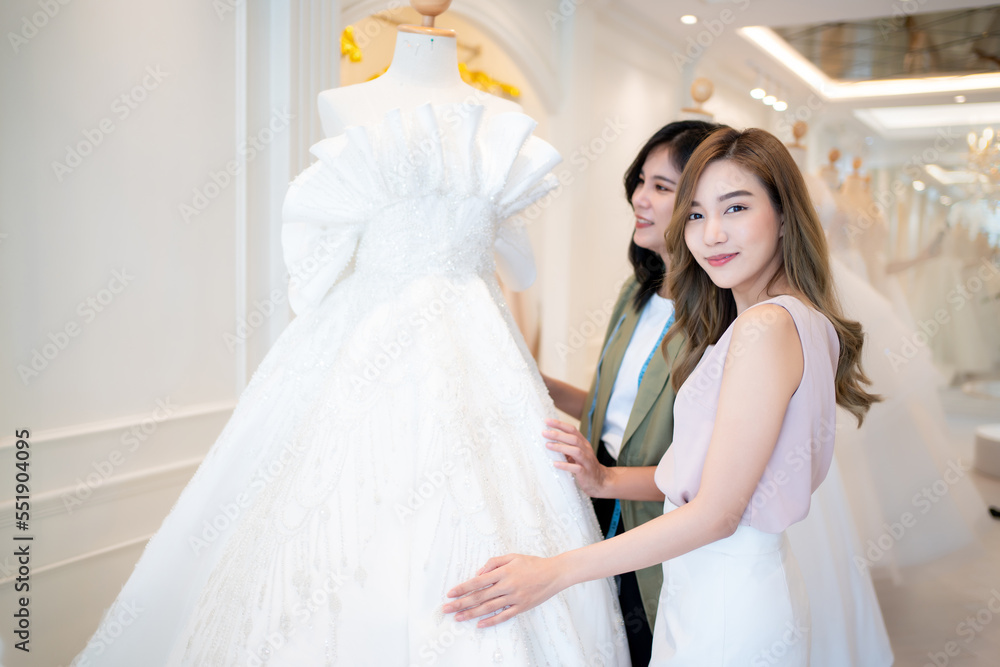 In the background of wedding dresses, an Asian woman designer manages a wedding business., Wedding designer and SME start up concept.