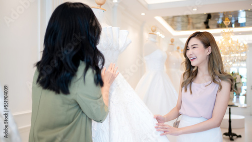 In the background of wedding dresses, an Asian woman designer manages a wedding business., Wedding designer and SME start up concept.