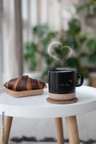 heart-shaped steaming coffee and croissant on white table. French breakfast. Copy space for your text