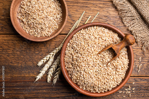 Wheat grains in bowl on a wooden background. Agriculture, harvest, bread baking concept