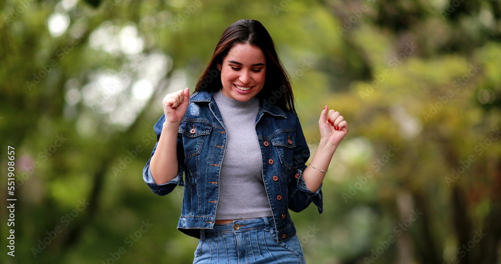 Happy young woman celebating success dancing outside in sunlight Happy young woman celebating success dancing outside in sunlight