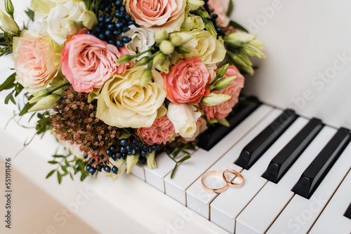 lush wedding bouquet and wedding rings on the piano keys