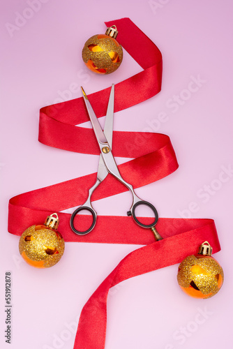 Professional scissors for cutting hair on a pink background with a Christmas decor. New Year, Christmas holidays, gifts in the field of hairdressing services
