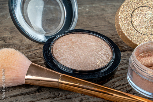 Face powder and bronzer background on a wooden table and a woman hand taking powder with brush.
