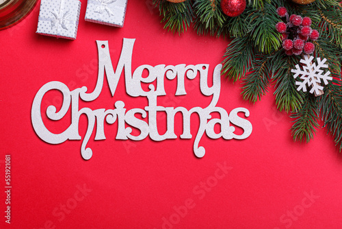 beautiful branches of a Christmas tree with cones and toys on a red background with the inscription Merry Christmas