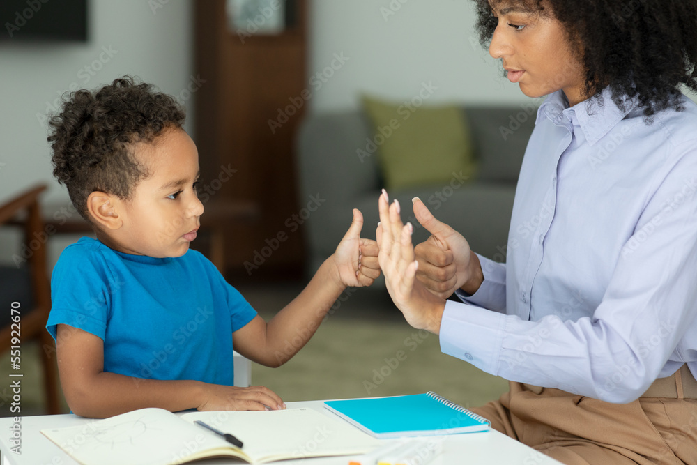 A smart boy counts on his fingers, studies with a private teacher in the office, a child learns numbers and how to count, sits at a table with a tutor A smart boy counts on his fingers, studies with a private teacher in the office, a child learns numbers and how to count, sits at a table with a tutor