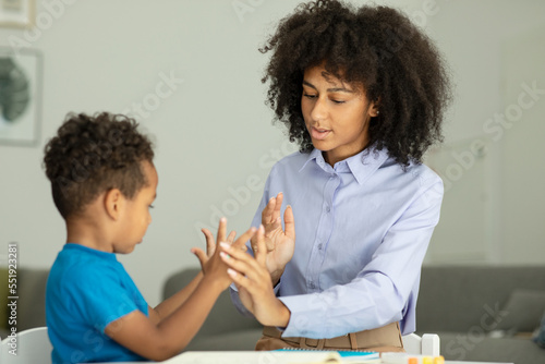 A smart boy counts on his fingers, studies with a private teacher in the office, a child learns numbers and how to count, sits at a table with a tutor photo