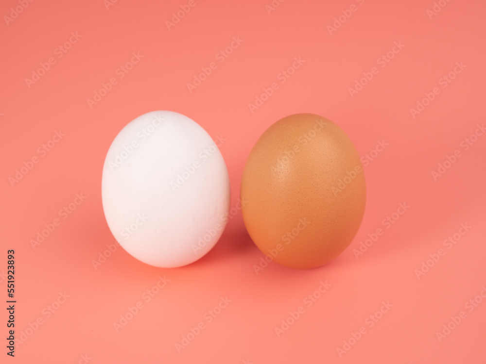 Fototapeta premium Chicken eggs on a pink background. White and brown egg on a pink background.