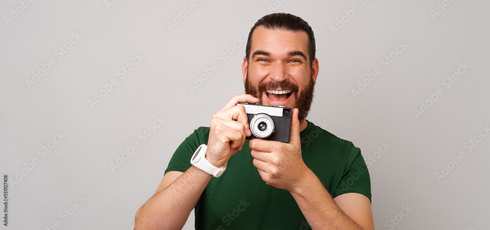 Banner size photo of a handsome man holding an old vintage photo camera. Studio shot over grey background. Banner size photo of a handsome man holding an old vintage photo camera. Studio shot over grey background.