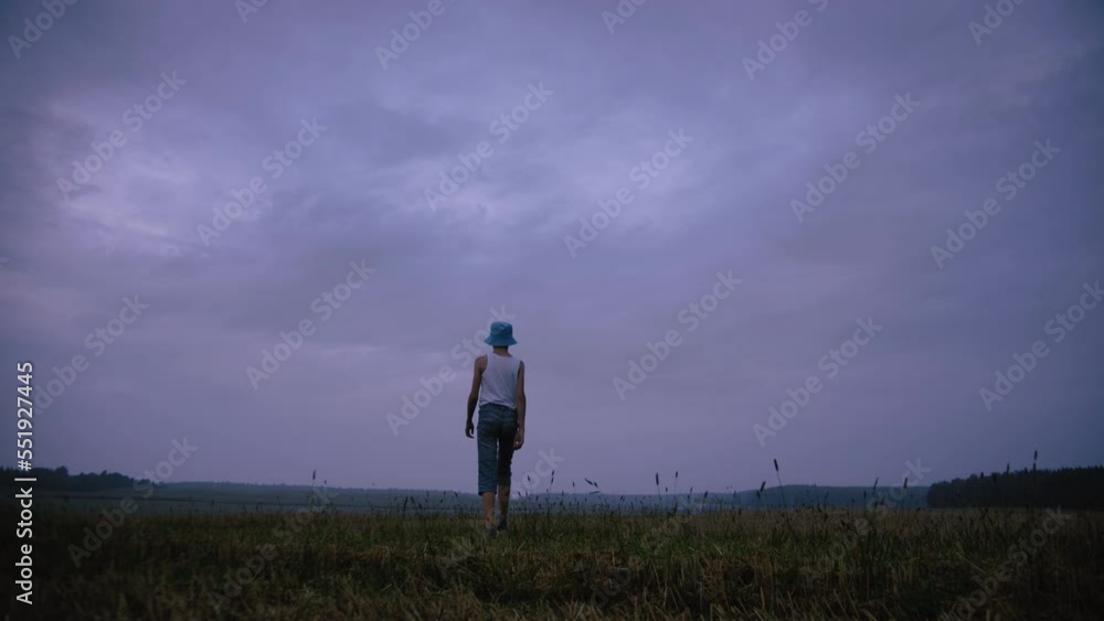 funny boy walks on a field in rainy weather in the evening, walk against the backdrop of beautiful rainy clouds, static shot funny boy walks on a field in rainy weather in the evening, walk against the backdrop of beautiful rainy clouds, static shot