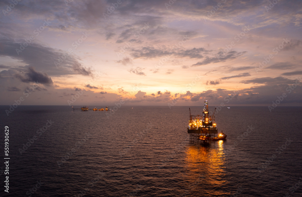 Jack up drilling rig and production platform in the middle of the ocean at sunrise time.