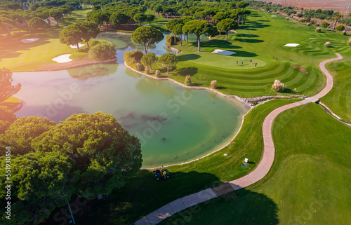 Green golf course luxury field with lake, aerial top view