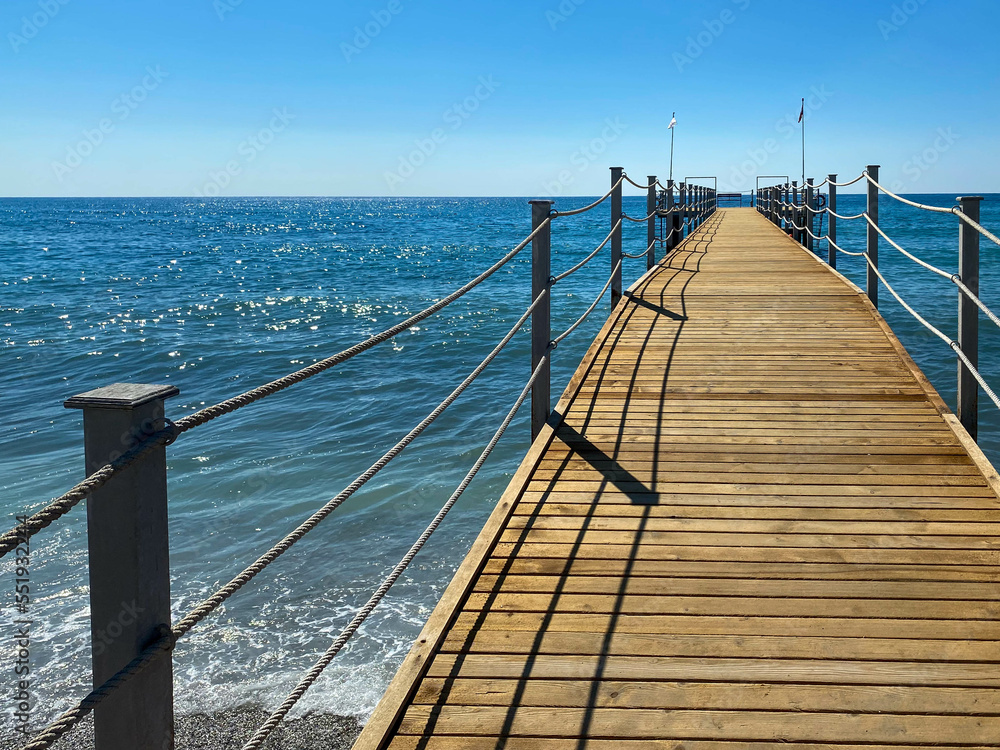 A wooden long pontoon, a pier with a rope railing on the sea on the beach on vacation in a paradise warm eastern tropical country resort