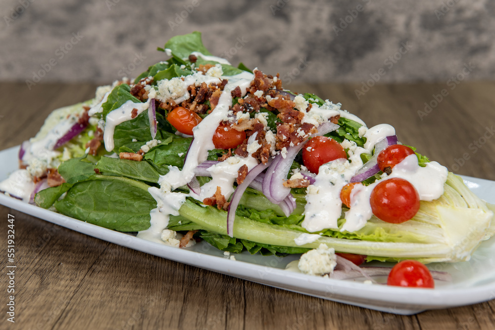 Very large romaine lettuce wedge salad piled high with fresh ingredients